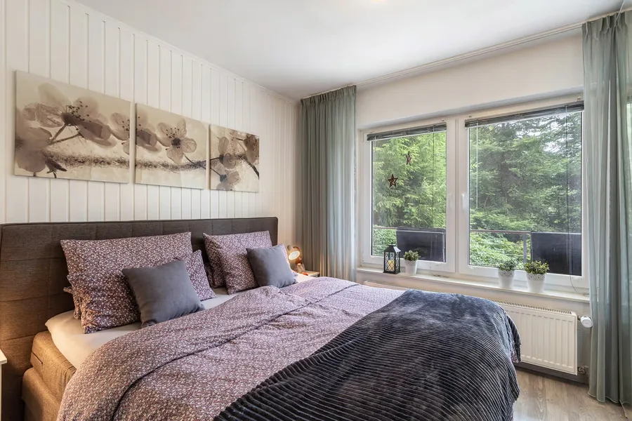 Schlafzimmer mit Boxspringbett und breitem Fenster
